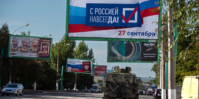 A military vehicle drives along a street with a billboard reading "With Russia forever, September 27" prior to a referendum in Luhansk, Luhansk People's Republic controlled by Russia-backed separatists, eastern Ukraine, Thursday, Sept. 22, 2022.