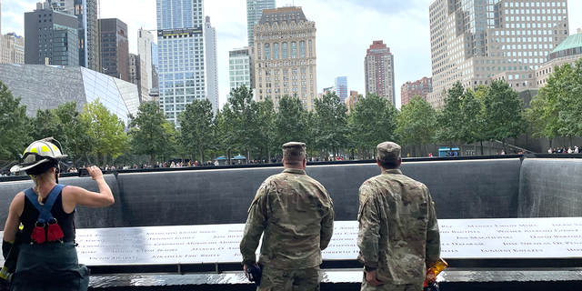 Two military servicemen and a firefighter take in the 9/11 memorial pools in Manhattan on Sept. 25, 2022.