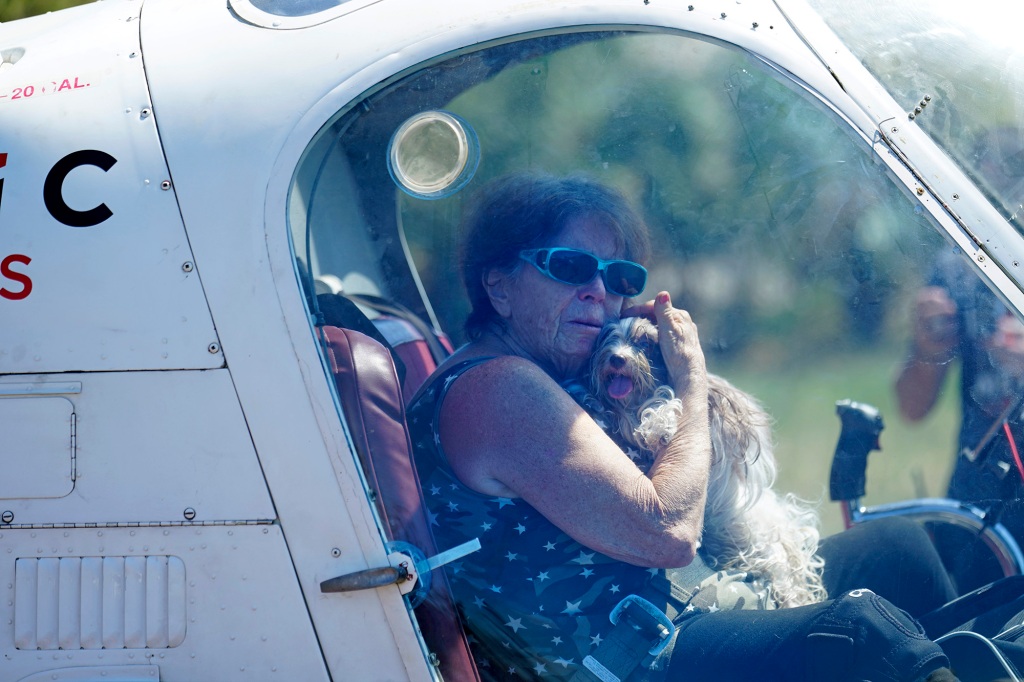 Helen Koch  holds one of her 17 dogs as she is evacuated by helicopter by members of mediccorps.org.