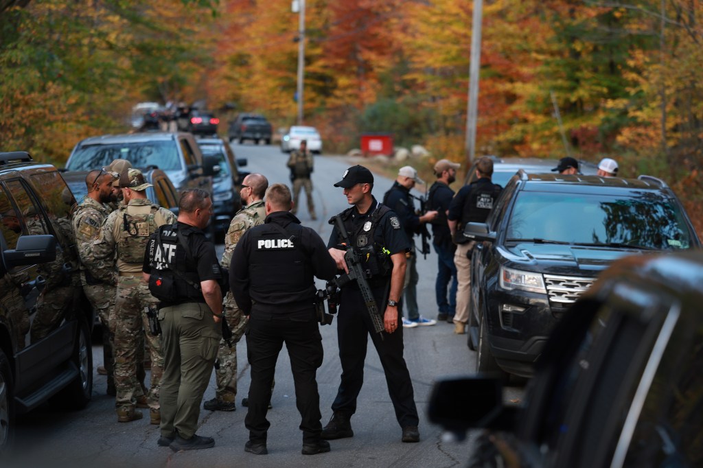 Police are pictured gathering on the road leading to the suspect's home on Thursday.